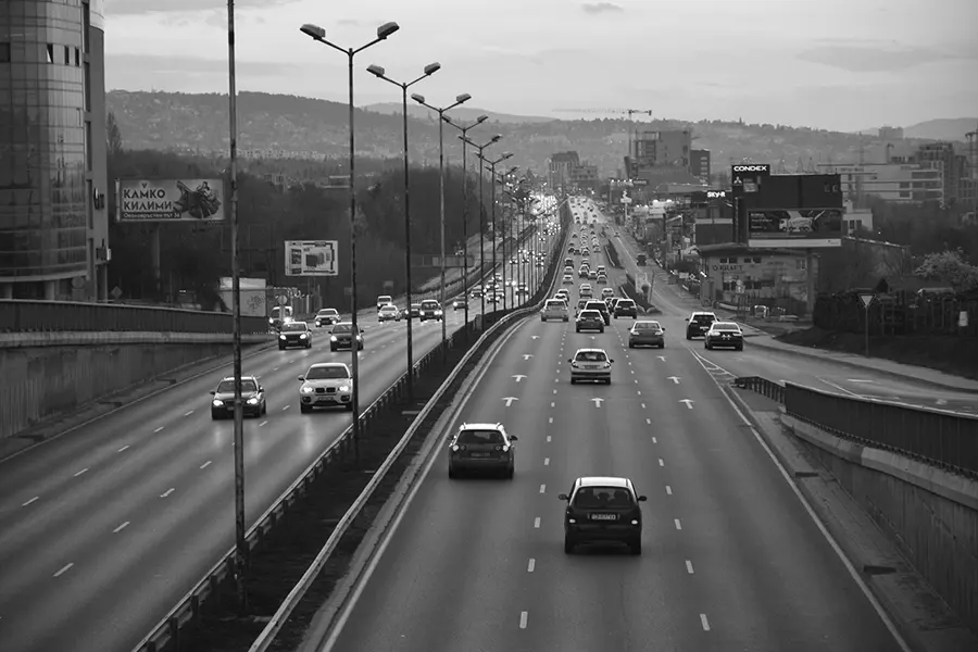 Photo d'une voie rapide en noir et blanc, avec des voitures roulant dans les deux sens de circulation